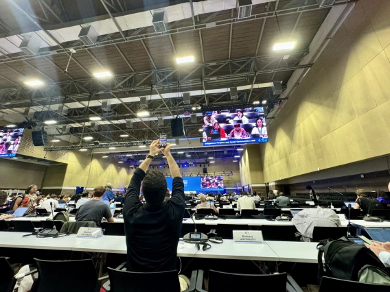 A man takes a picture with arms held high of a crowed room of delegates.