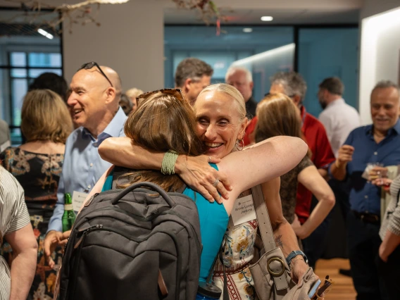 Two women embrace in a crowd.