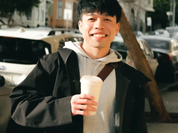 Man holding coffee cup on busy San Francisco street.