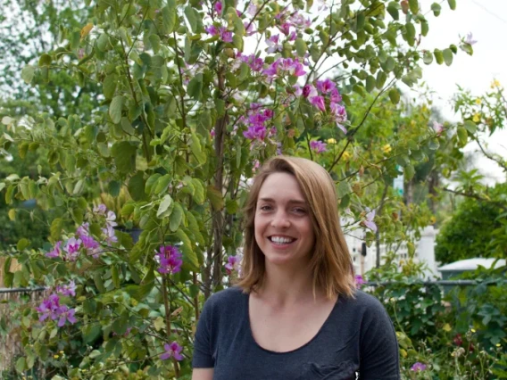 Woman in front of blooming bush.