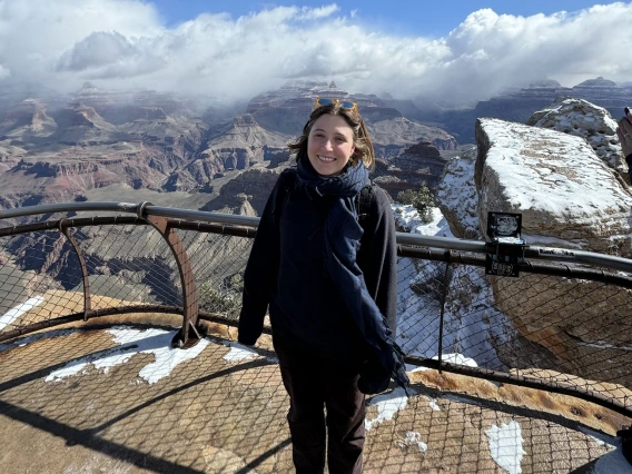 Woman stands in front of a snowy grand canyon
