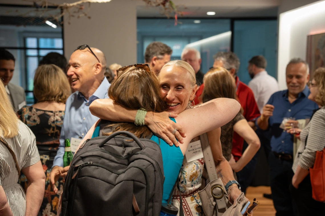 Two women embrace in a crowd.