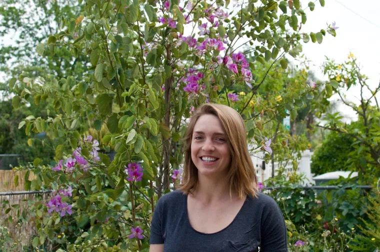 Woman in front of blooming bush.