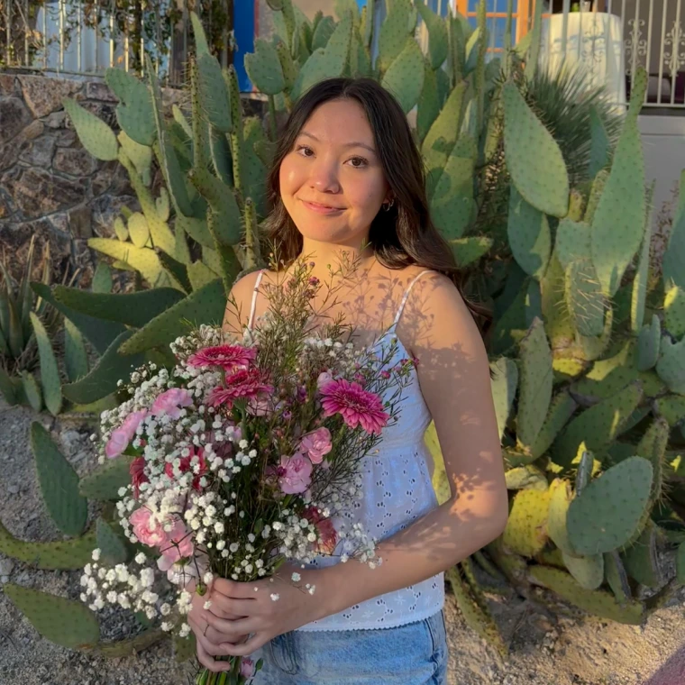 Amy holding a bouquet in front of a large green cactus