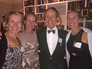 A group stands together smiling in evening attire: three blonde women with their father, an older gentleman with greying hair and glasses.