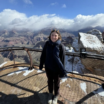 Woman stands in front of a snowy grand canyon