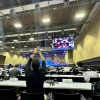 A man takes a picture with arms held high of a crowed room of delegates.