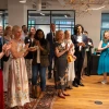 A crowd in formal dress applaud. 